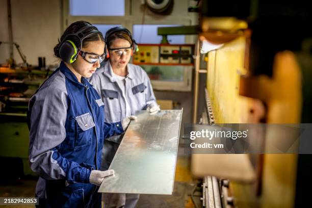 professional female workers operating industrial press brake - aluminium stockfoto's en -beelden