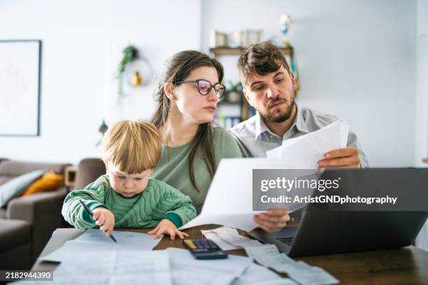 young family managing budget and paying bills and taxes. - finanças domésticas imagens e fotografias de stock