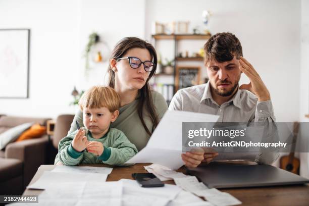young family managing budget and paying bills and taxes. - costo fotografías e imágenes de stock