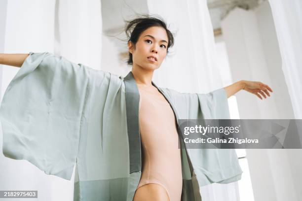 portrait of beautiful young japanese woman in light blue national kimono dancing on white background - wabi sabi stock pictures, royalty-free photos & images