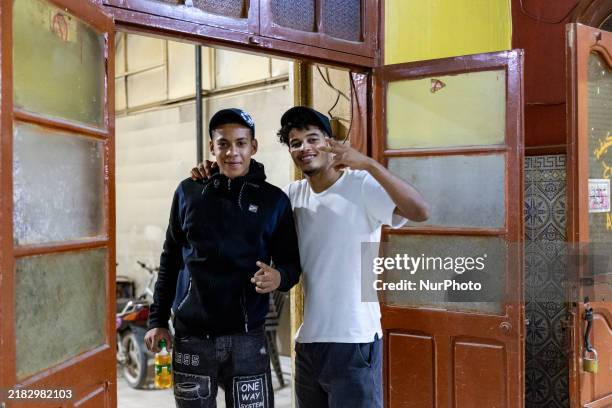 Young men pose to be photographed in a coffee shop in Tozeur in central Tunisia on October 28, 2024.