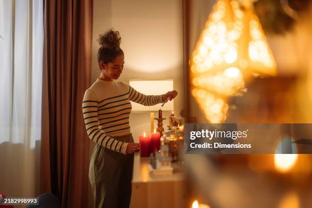 woman lighting candles on a dresser at home creating a warm atmosphere - hot indoors stock pictures, royalty-free photos & images