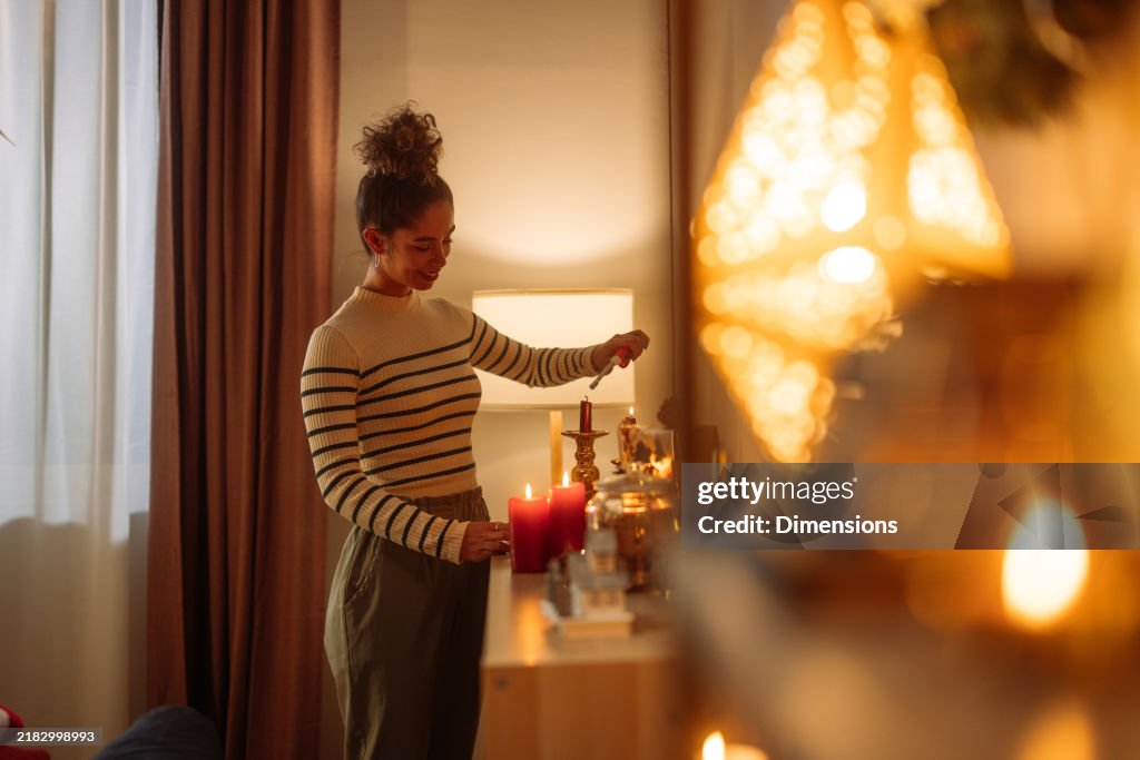 Mulher acendendo velas em uma cômoda em casa, criando uma atmosfera acolhedora