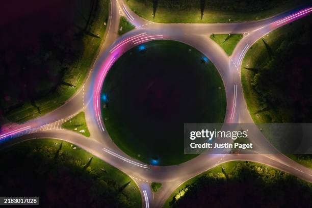 drone/aerial view of traffic moving around a roundabout at night - contrasts stock pictures, royalty-free photos & images