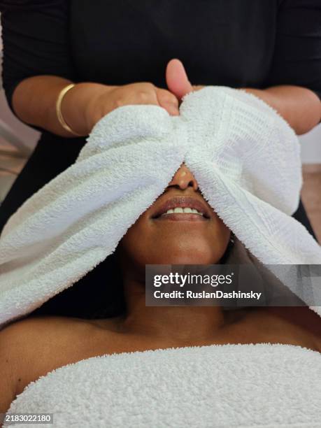 relaxing warm towel facial treatment. - towel dispenser stock pictures, royalty-free photos & images
