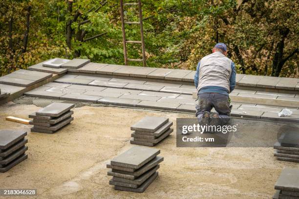 bauarbeiter bei der verlegung von zementziegeln im außenbereich - betonmischmaschine stock-fotos und bilder