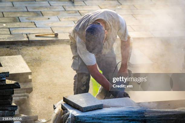 skilled worker precisely slicing cement bricks for flooring - circular saw stock pictures, royalty-free photos & images