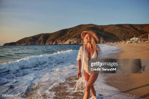 beautiful woman running inside water on the beach at sunset - beach holiday stock pictures, royalty-free photos & images