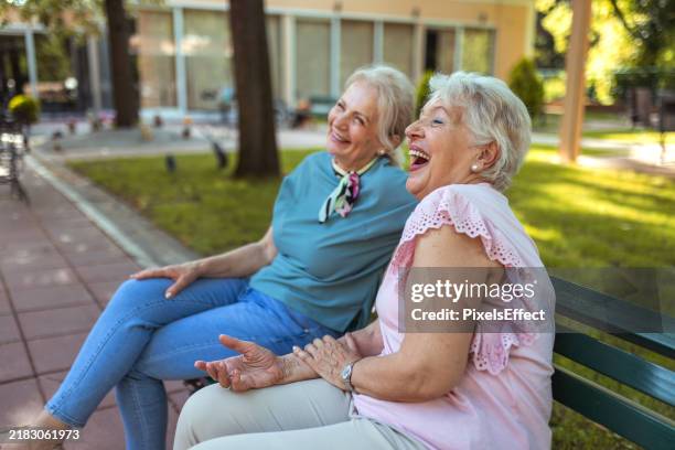 two cheerful female pensioner relaxing and talking - retirement community stock pictures, royalty-free photos & images
