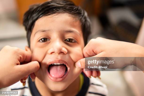 pov hand pulling cheeks of little boy. - cheek pinching stock pictures, royalty-free photos & images