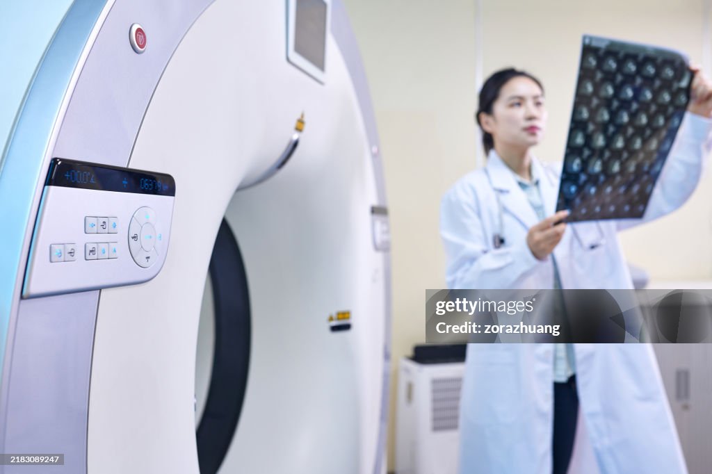 Female Doctor Checking MRI Film beside MRI-scanner