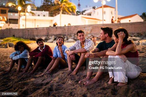 young friends talking on the beach - mexico beach night stock pictures, royalty-free photos & images