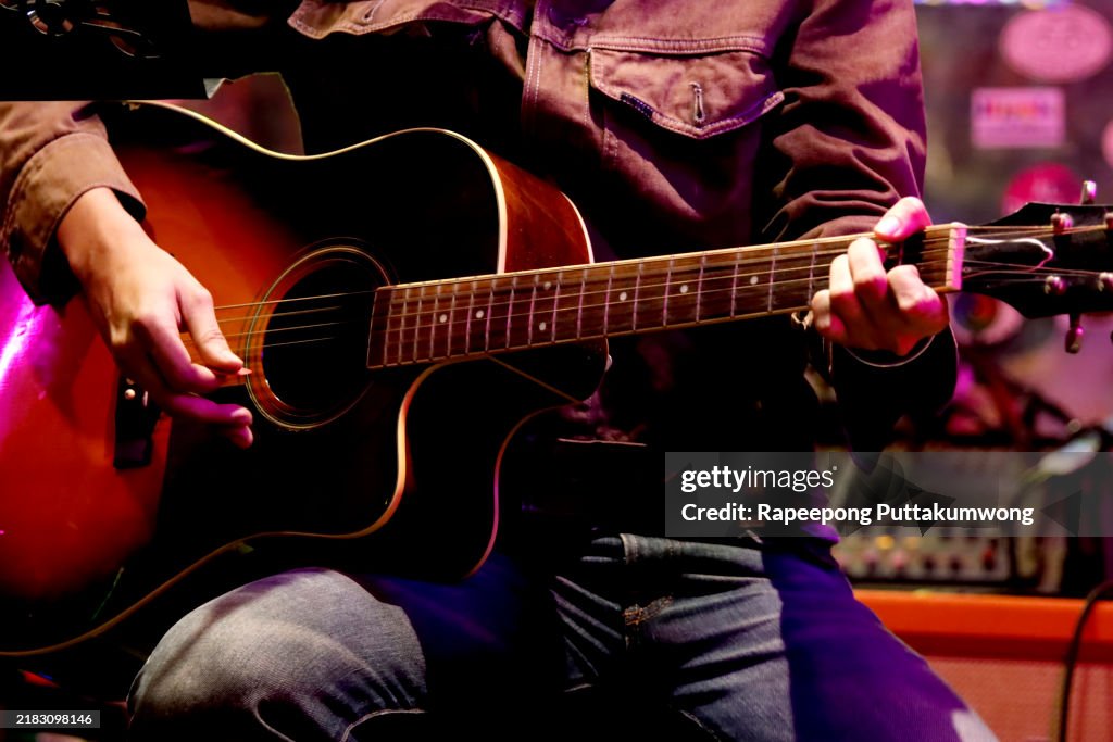 Man's hands playing acoustic guitar at a small concert