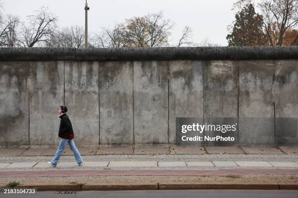 Person walks by the Berlin Wall fragment on 35th Berlin Wall fall anniversary in Berlin, Germany on November 9, 2024.