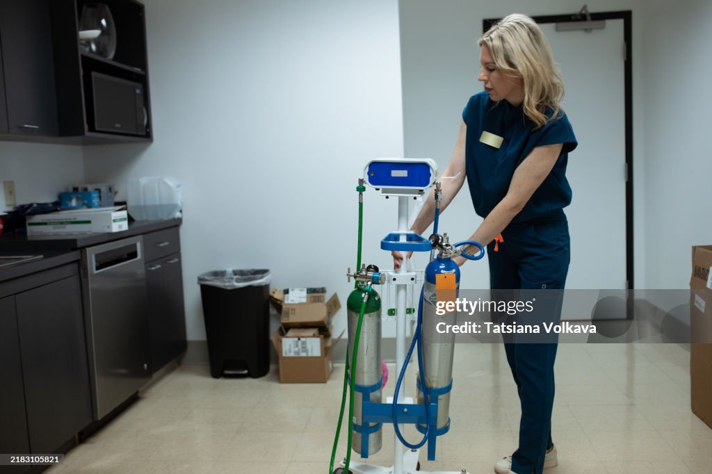 Woman in medical attire prepares a portable device that delivers a blend of oxygen and nitrous oxide for pain relief.