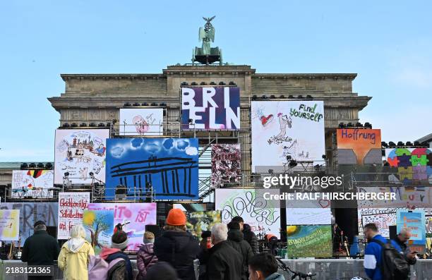 People look at screens displaying artworks at Brandenburg gate ahead of celebrations marking the 35th anniversary of the fall of the Berlin Wall in...