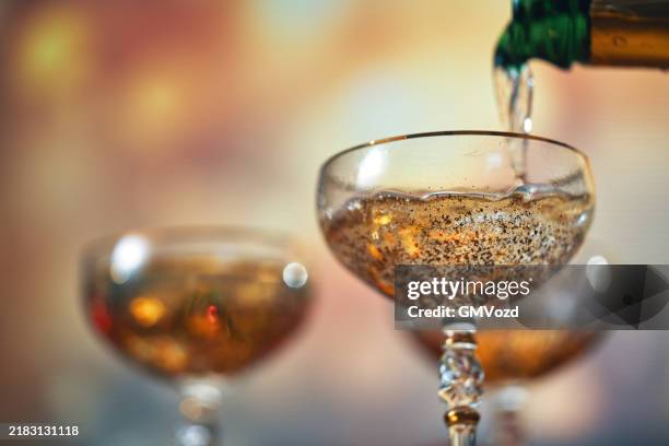 pouring champagne into champagne flutes for christmas holidays - champanhe imagens e fotografias de stock