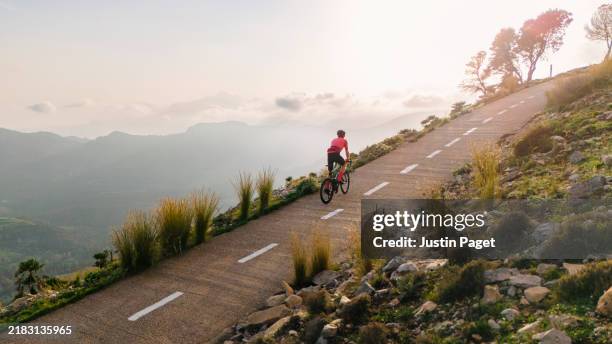 mature cyclist on a steep climb in the spanish mountains at sunset - cuesta arriba fotografías e imágenes de stock