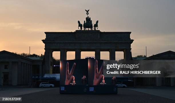 Screens display historic footage at the Brandenburg gate during celebrations marking the 35th anniversary of the fall of the Berlin Wall in Berlin on...
