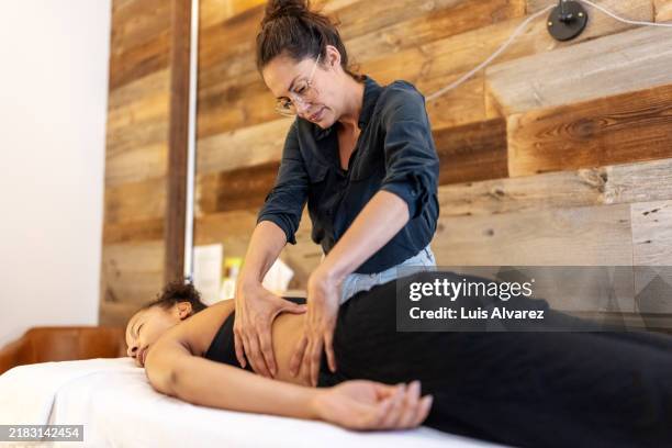 therapist providing lower back massage for pain relief - kinésithérapie photos et images de collection