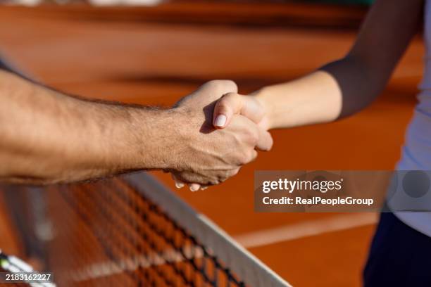 handschlag über das tennisplatznetz, sonnige tagesszene - fairness stock-fotos und bilder