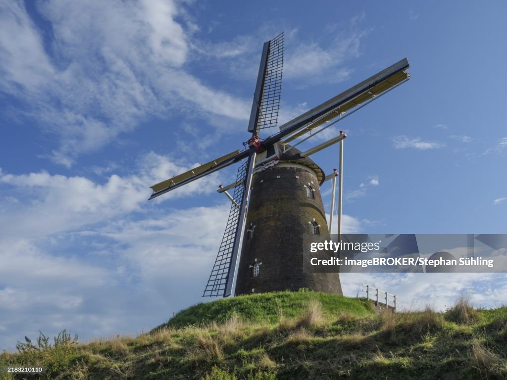 Old windmill on a green meadow under a blue sky with white clouds, old windmill on a green hill in the netherlands, Bredevoort, netherlands