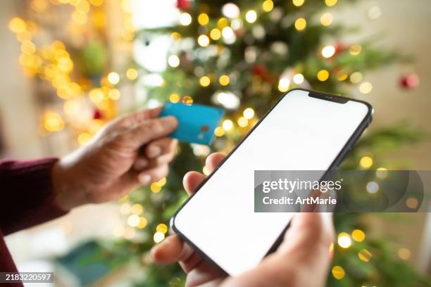 mann mit smartphone und kreditkarte in der nähe von weihnachtsbaum - wirtschaftskriminalität stock-fotos und bilder