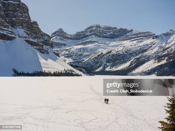 two people walking on frozen lake - banff stock pictures, royalty-free photos & images