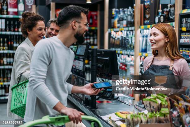 mann benutzt telefon, um die zahlung im supermarkt zu tätigen - markt verkaufsstätte stock-fotos und bilder