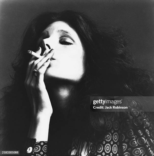 Headshot of Ruby Lynn Reyner, actress, smoking a cigarette, wearing a shirt with large circular designs.