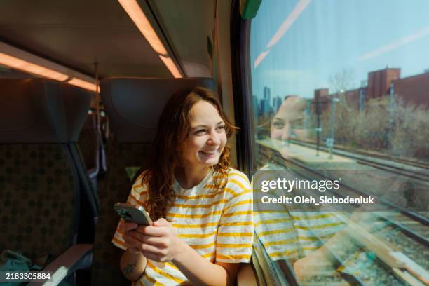 woman using smartphone and looking through the window traveling by train in canada - tåg bildbanksfoton och bilder