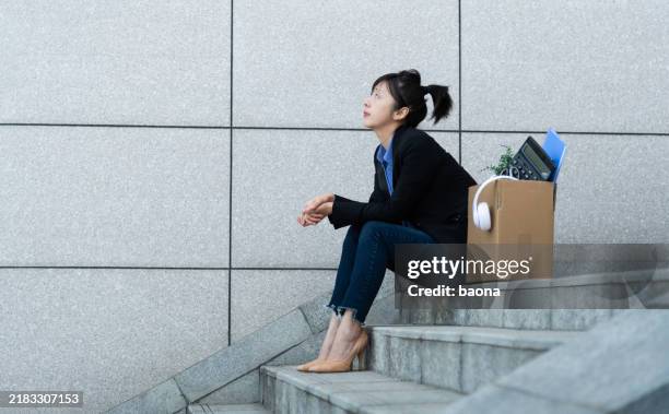 mujer desempleada sentada fuera del edificio de oficinas - depresión económica fotografías e imágenes de stock