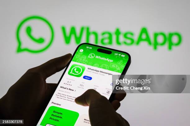 Person holds a smartphone displaying the WhatsApp app page, with the WhatsApp logo in the background, on November 6, 2024 in Chongqing, China....