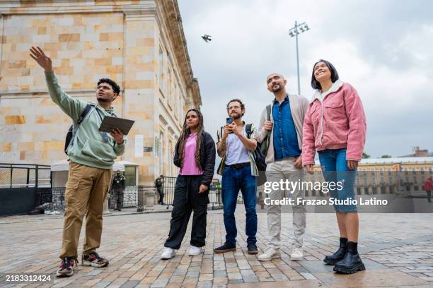 reiseleiter mit digitalem tablet und gespräch mit touristen in der altstadt von bogotá - reiseführer stock-fotos und bilder