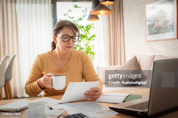 woman reading documents and calculating home finances - annual event stock pictures, royalty-free photos & images
