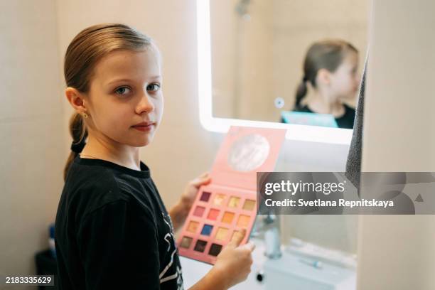teenage girl applying makeup while standing in front of a touch mirror in the bathroom - body conscious stock pictures, royalty-free photos & images