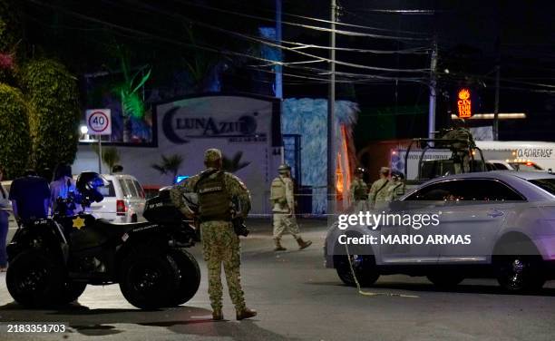 Mexican Army soldiers and public security agents stand guard outside the Los Cantaritos bar where an armed group broke in on the eve, killing ten...