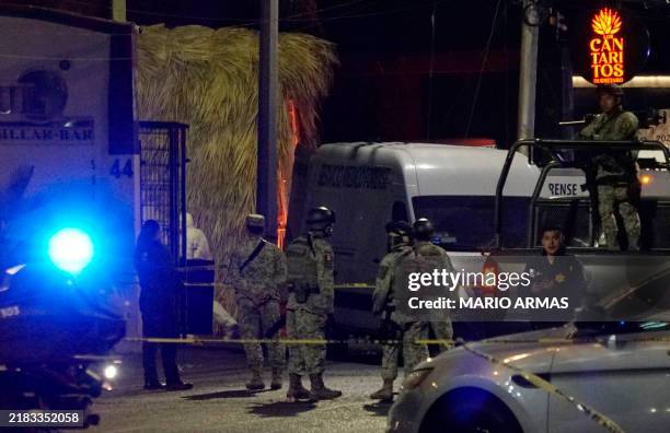 Mexican Army soldiers and public security agents stand guard outside the Los Cantaritos bar where an armed group broke in on the eve, killing ten...