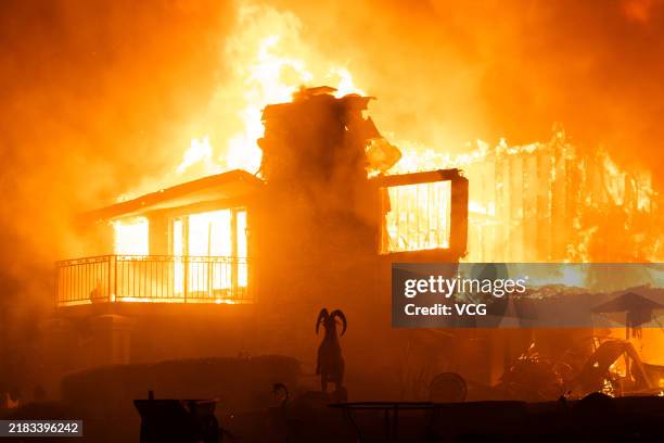 Flames engulf a structure during a fast-moving wildfire on November 6, 2024 in Moorpark, California. California is being lashed by powerful winds...