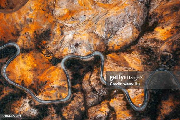 aerial view of rock surface as moonscape and winding road in the mountains of queenstown - tasmanien stock-fotos und bilder
