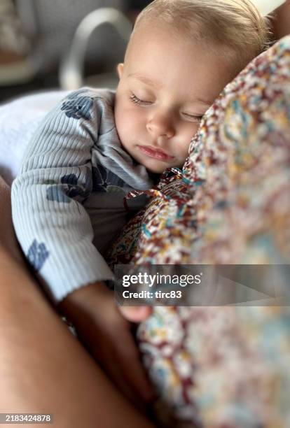 one year old baby girl asleep in mother arms - babyhood stock pictures, royalty-free photos & images