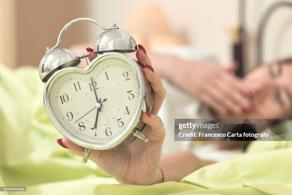 Woman touching alarm clock at bedroom