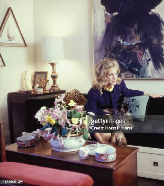 Christian Dior Press Relations Manager Robin Butler at home in her New York City apartment, seated on a green velvet banquette sofa with a painting...