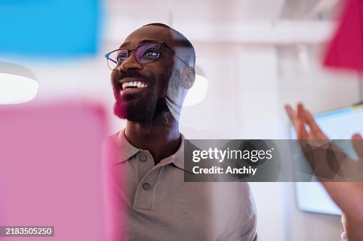 Portrait of a black man presenting his ideas on a glass wall during a business meeting Portrait of a black man presenting his ideas on a glass wall during a business meeting