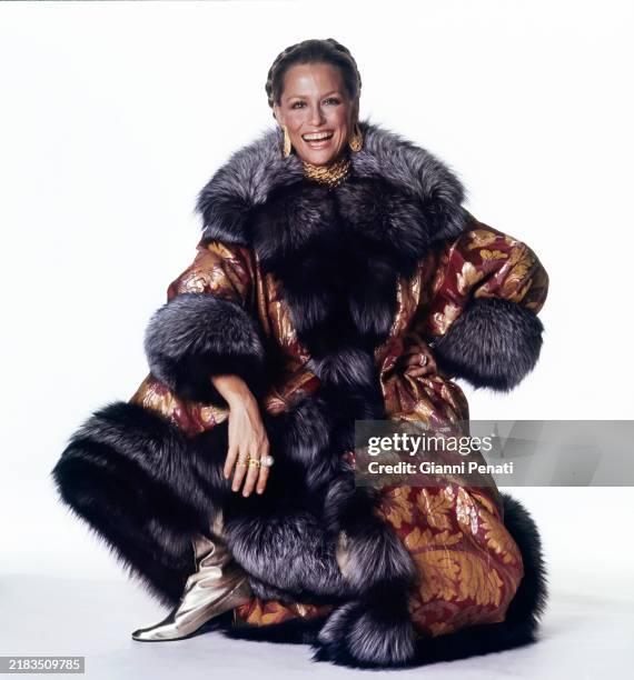 Model Lauren Hutton, wearing a purple and gold leaf-patterned brocade caftan with silver fox trim at collar, front, cuffs and hem by Maximilian,...