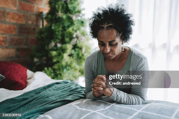 mature woman praying in bedroom - please use this photo not the other one stock pictures, royalty-free photos & images