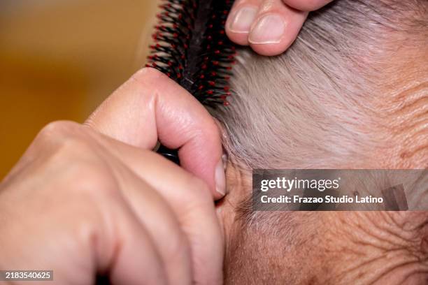 nahaufnahme eines älteren mannes, der sich die haare kämmt - öffentlicher auftritt stock-fotos und bilder