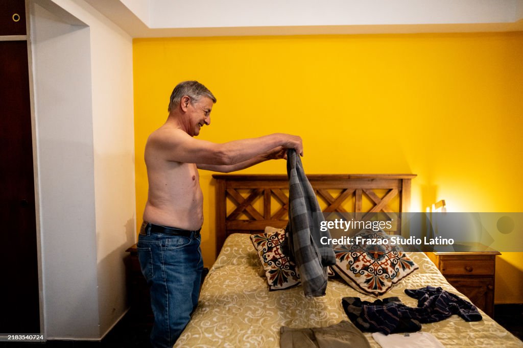Senior man getting dressed in a bedroom at home