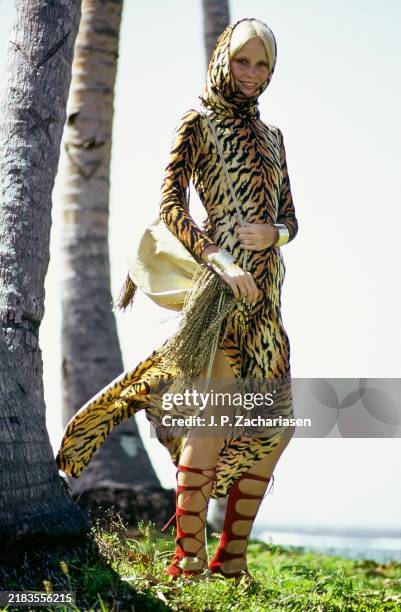 Model Gunilla Lindblad stands on the island of Fiji. She is wearing a Ban-Lon tiger print hooded robe by Scott Barrie for Barrie Sport, in Antron...