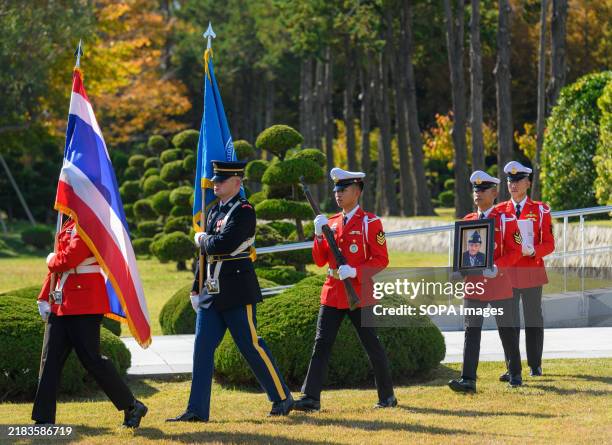 An honor guard holds a portrait while another holds the remains of Thailand's Korean War veteran Rod Asapanan, during the burial ceremony at the...